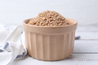 Photo of Buckwheat bran in bowl on white wooden table, closeup