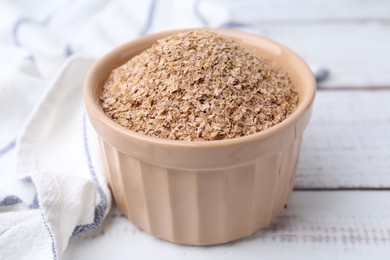 Photo of Buckwheat bran in bowl on white wooden table, closeup