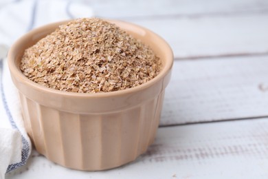 Photo of Buckwheat bran in bowl on white wooden table, closeup. Space for text