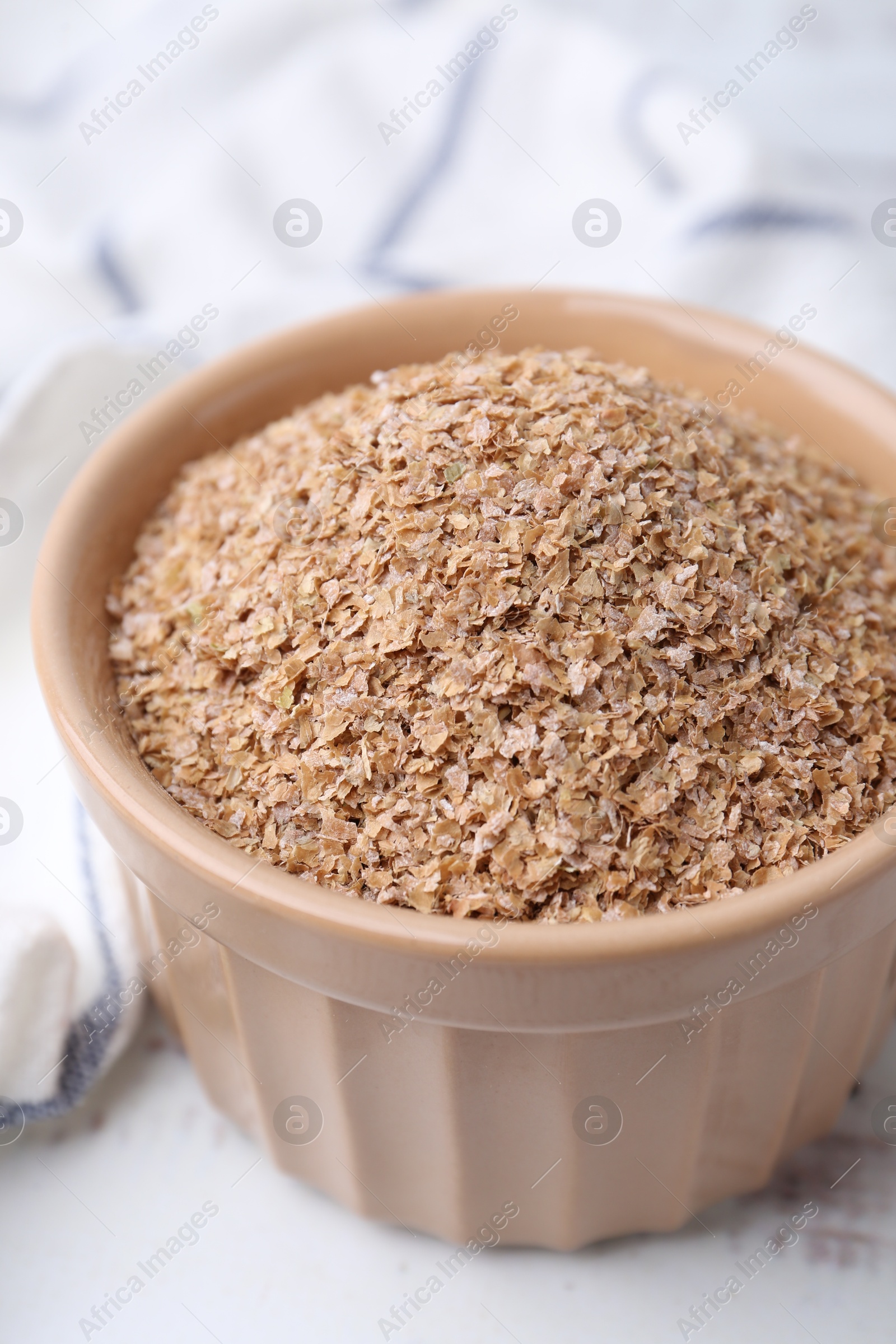 Photo of Buckwheat bran in bowl on white table, closeup