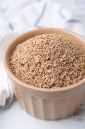 Photo of Buckwheat bran in bowl on white table, closeup