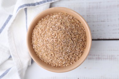 Buckwheat bran in bowl on white wooden table, top view