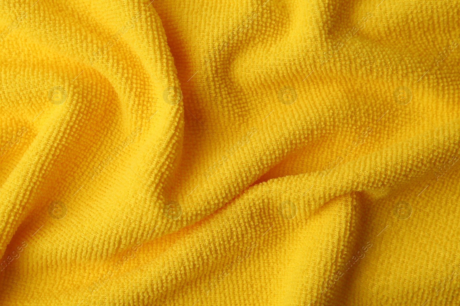 Photo of Clean yellow microfiber cloth as background, top view