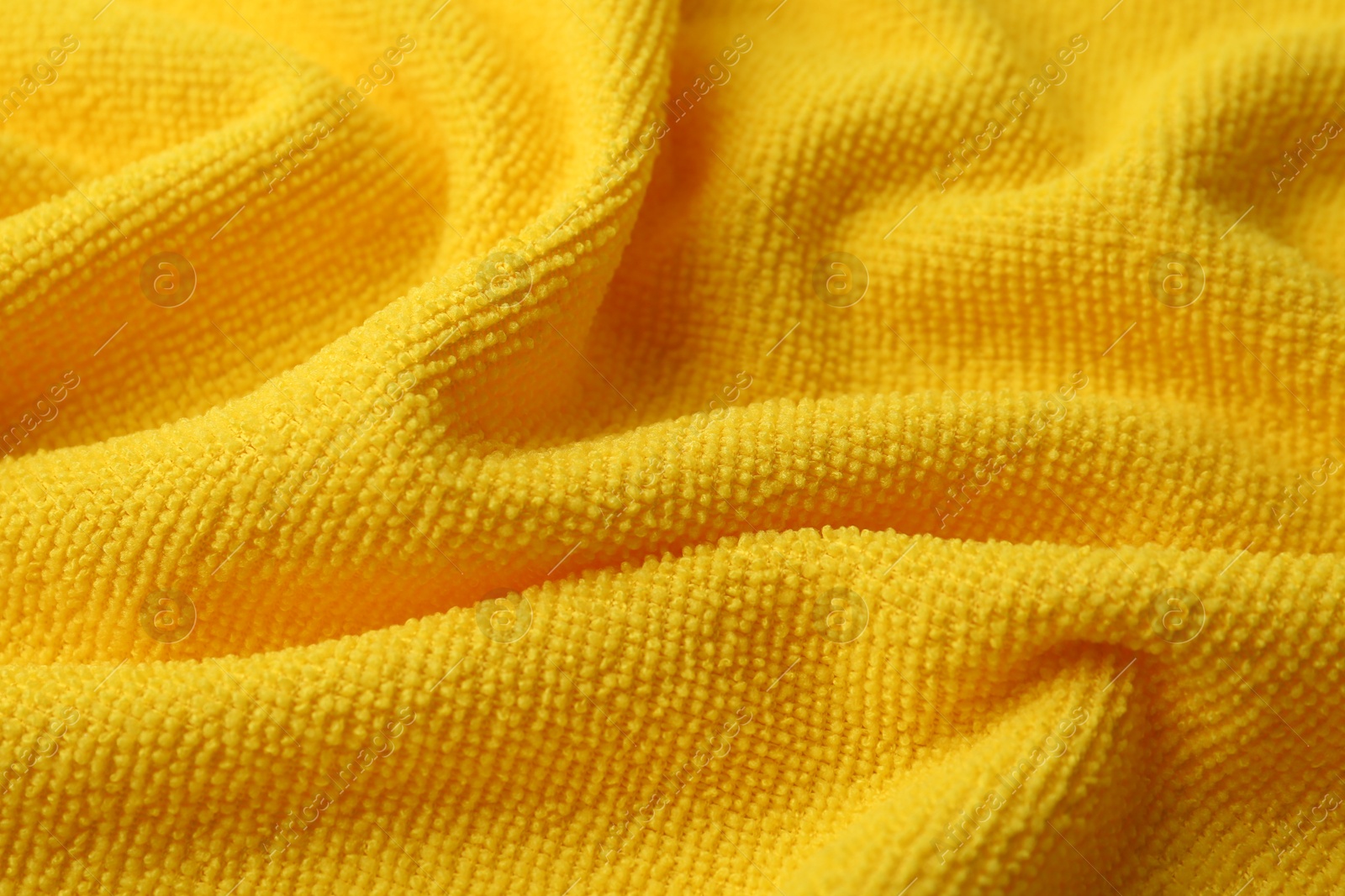 Photo of Clean yellow microfiber cloth as background, closeup