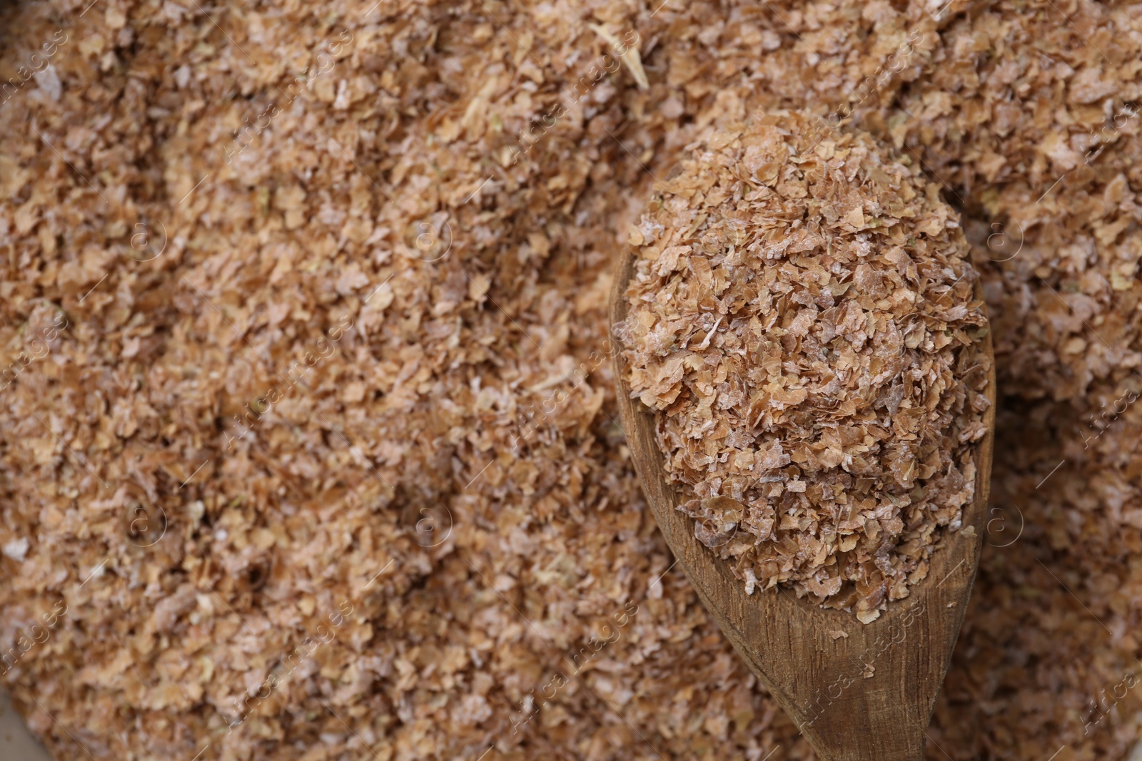 Photo of Pile of buckwheat bran and wooden spoon, above view