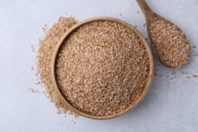 Photo of Buckwheat bran in bowl and spoon on light grey table, top view