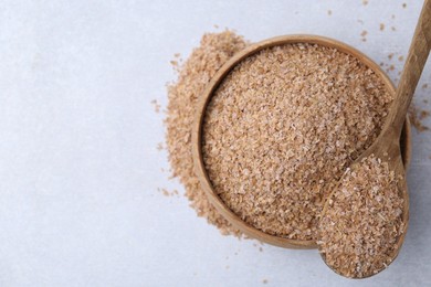 Photo of Buckwheat bran in bowl and spoon on light grey table, top view. Space for text