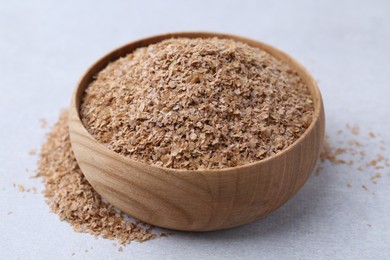 Photo of Buckwheat bran in bowl on light grey table, closeup