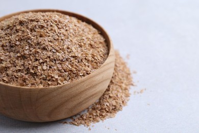 Buckwheat bran in bowl on light grey table, closeup. Space for text