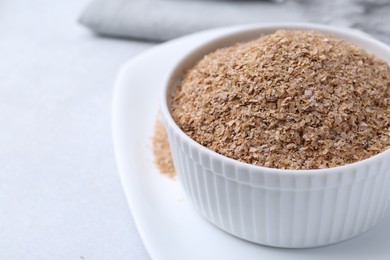 Photo of Buckwheat bran in bowl on light grey table, closeup