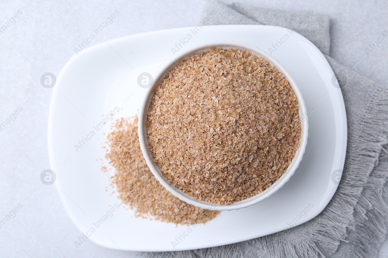 Photo of Buckwheat bran in bowl on light grey table, top view