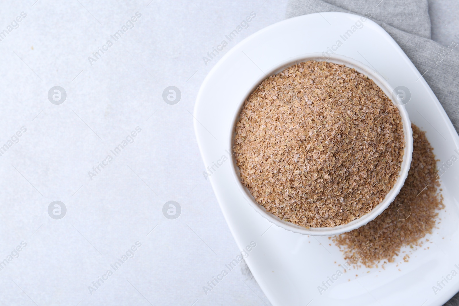 Photo of Buckwheat bran in bowl on light grey table, top view. Space for text