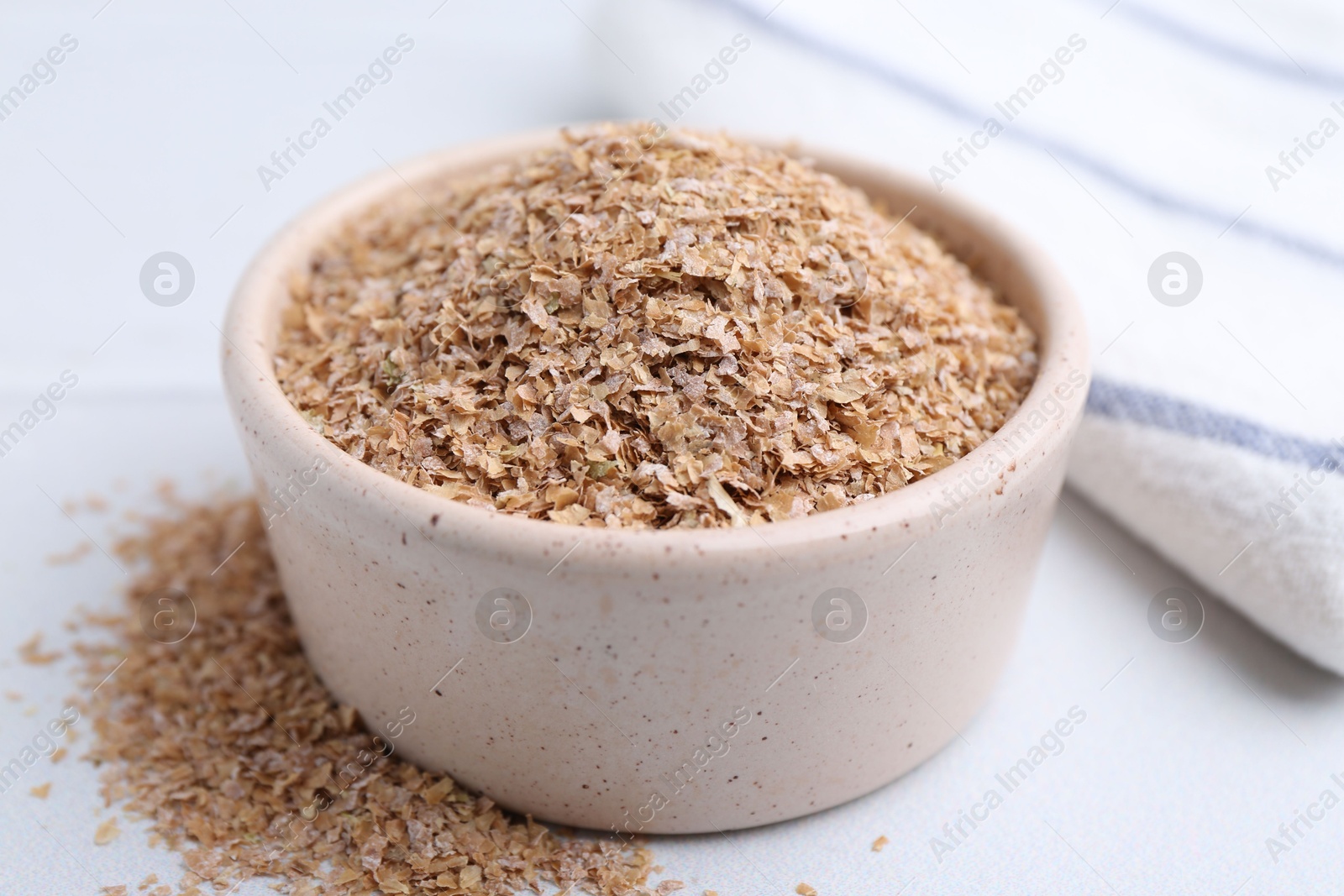 Photo of Buckwheat bran in bowl on white table, closeup