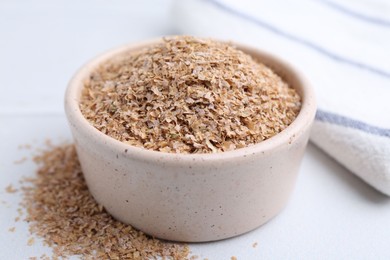 Buckwheat bran in bowl on white table, closeup