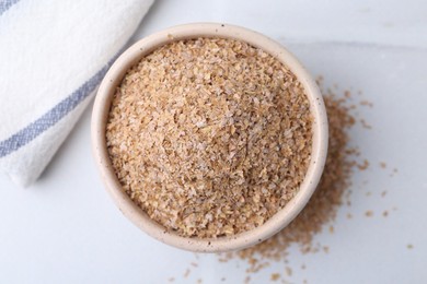 Buckwheat bran in bowl on white table, top view