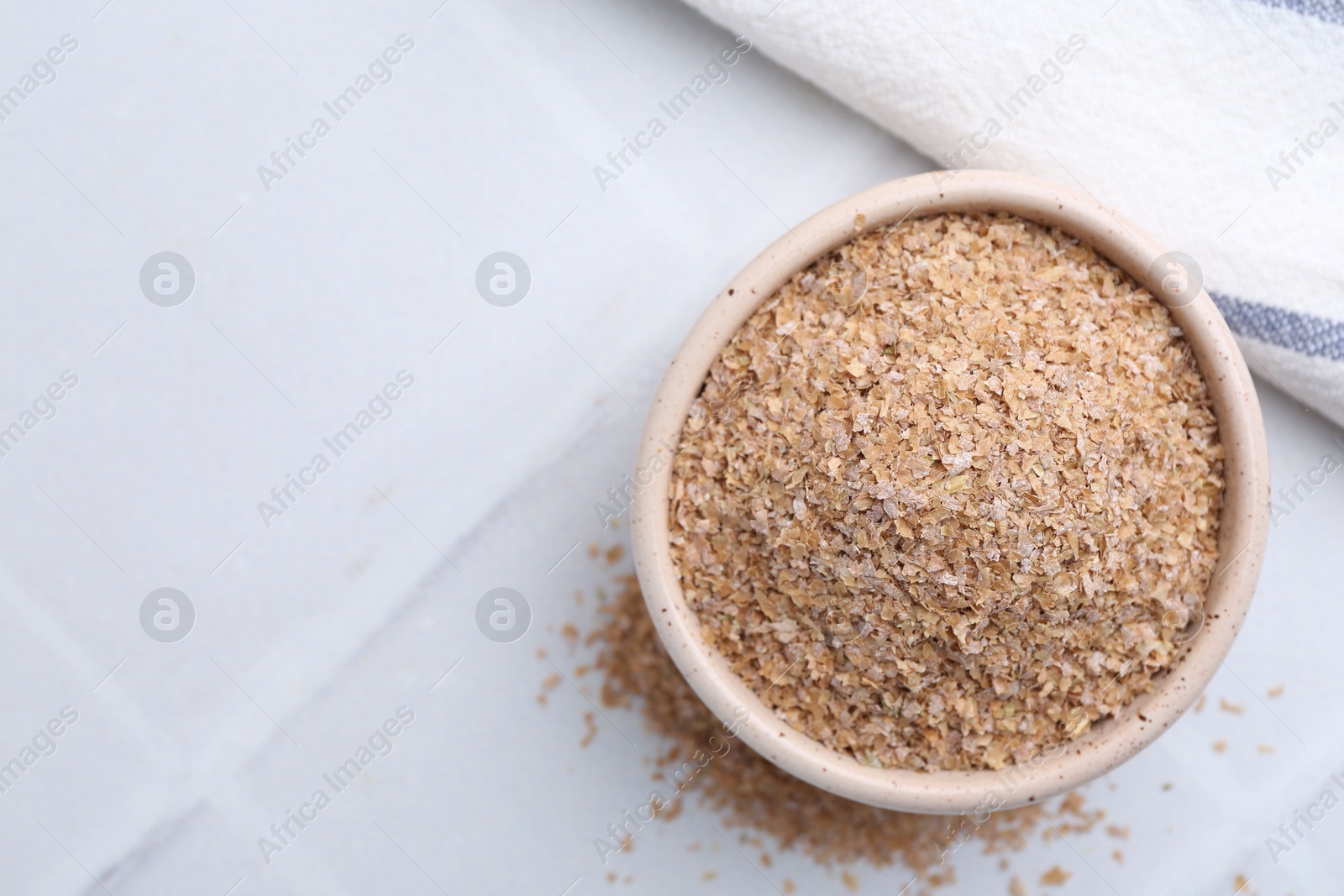 Photo of Buckwheat bran in bowl on white table, top view. Space for text