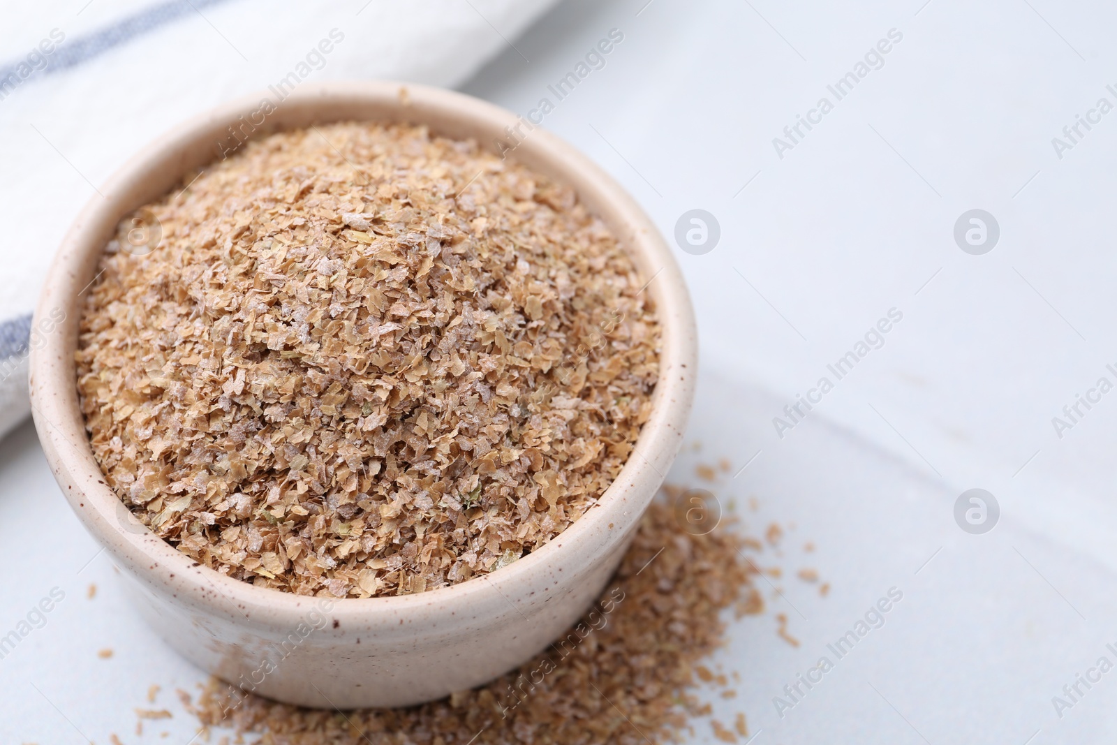 Photo of Buckwheat bran in bowl on white table, closeup. Space for text