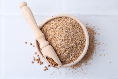 Photo of Buckwheat bran in bowl and grains on white table, top view