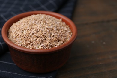 Photo of Buckwheat bran in bowl on wooden table, closeup. Space for text