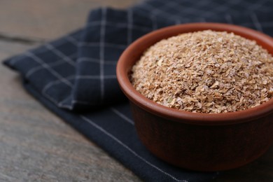 Buckwheat bran in bowl on wooden table, closeup