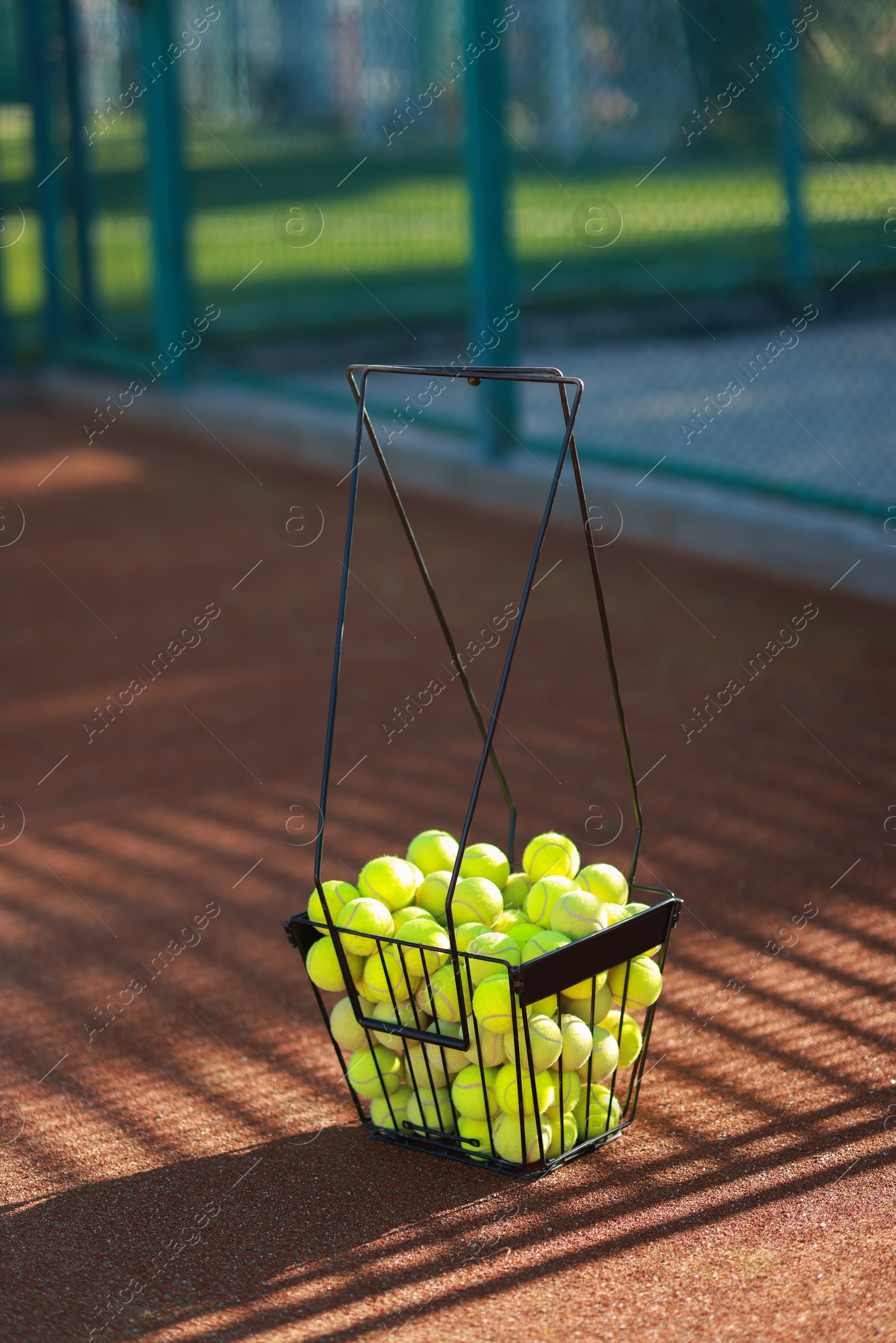 Photo of Many tennis balls in metal basket on court