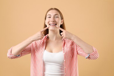 Photo of Girl pointing at her braces on beige background