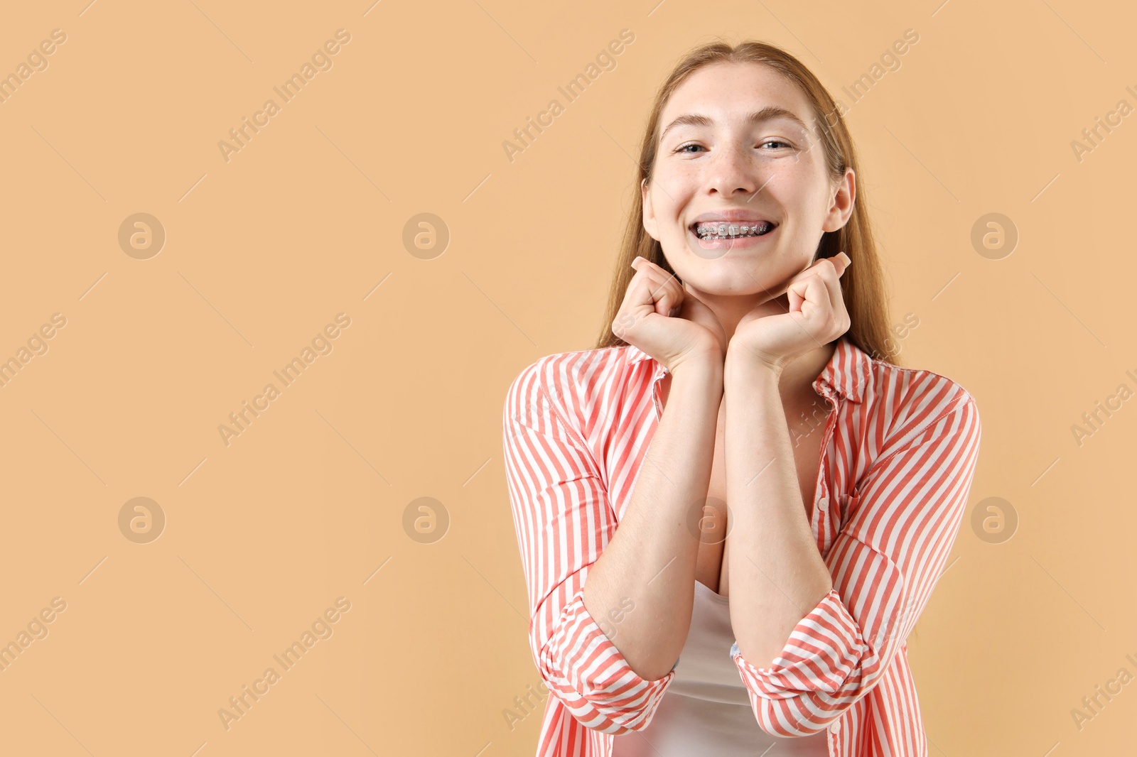 Photo of Smiling girl with braces on beige background, space for text