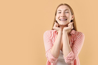 Photo of Smiling girl with braces on beige background, space for text