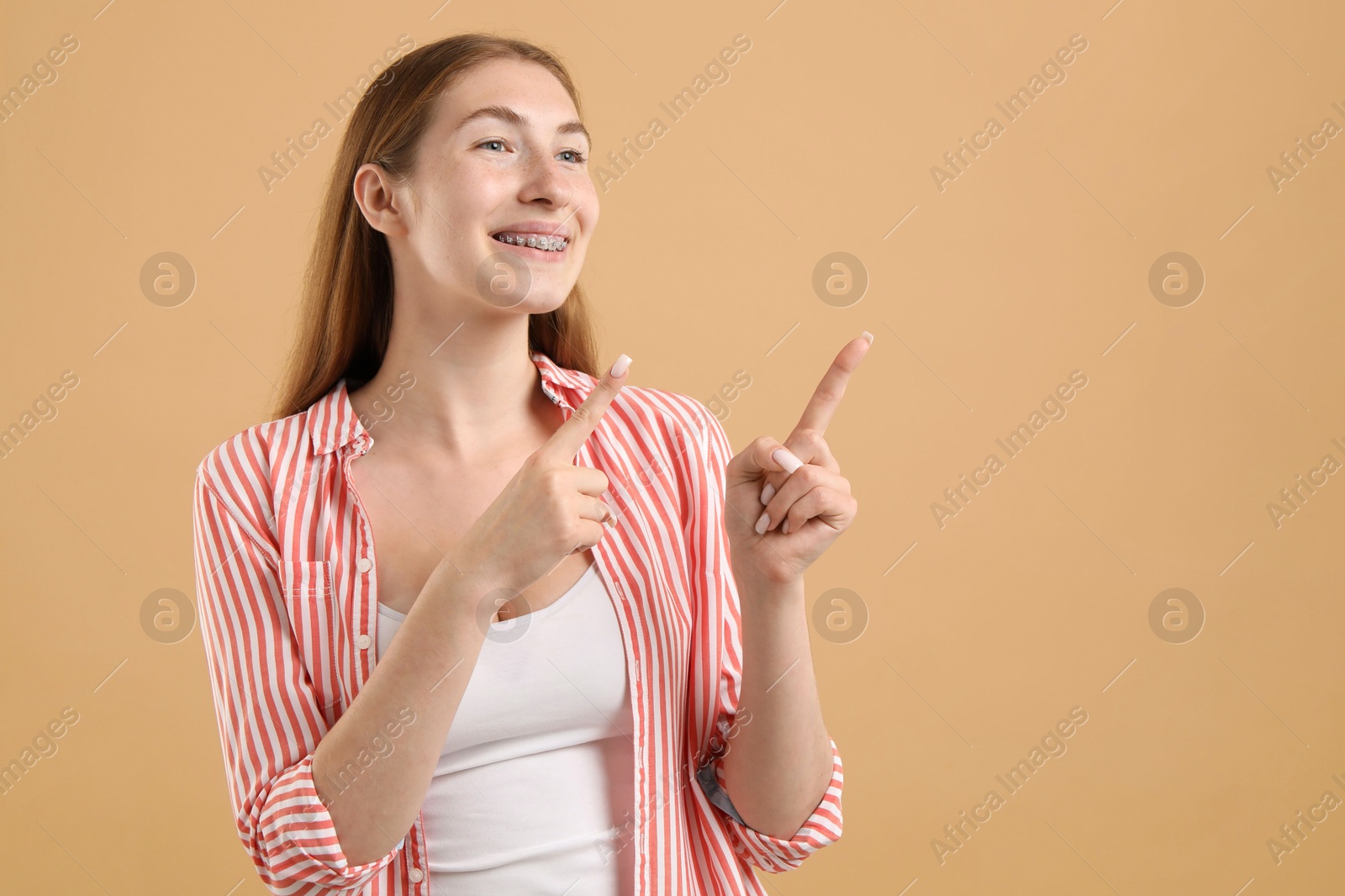 Photo of Smiling girl with braces on beige background, space for text