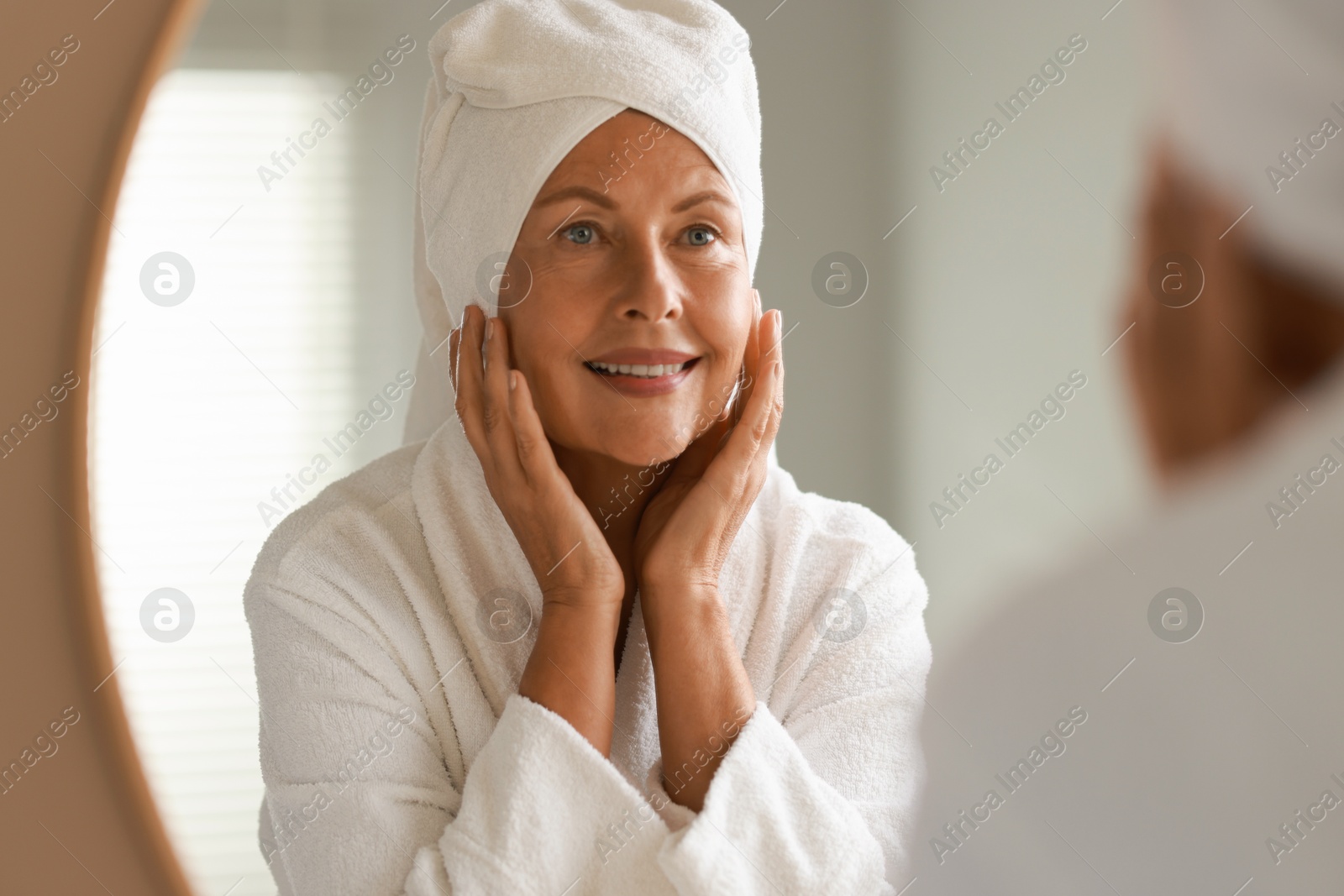 Photo of Face massage. Beautiful woman with healthy skin near mirror at home