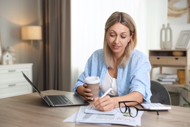 Photo of Budget planning. Woman with coffee taking notes at table indoors