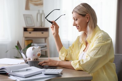 Budget planning. Woman using laptop at table indoors