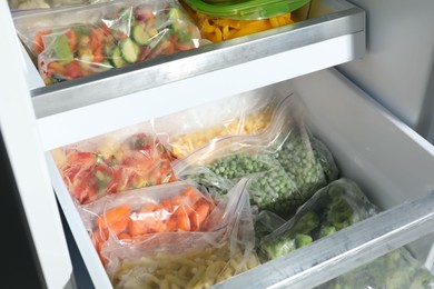 Photo of Plastic bags with different frozen vegetables in refrigerator, closeup