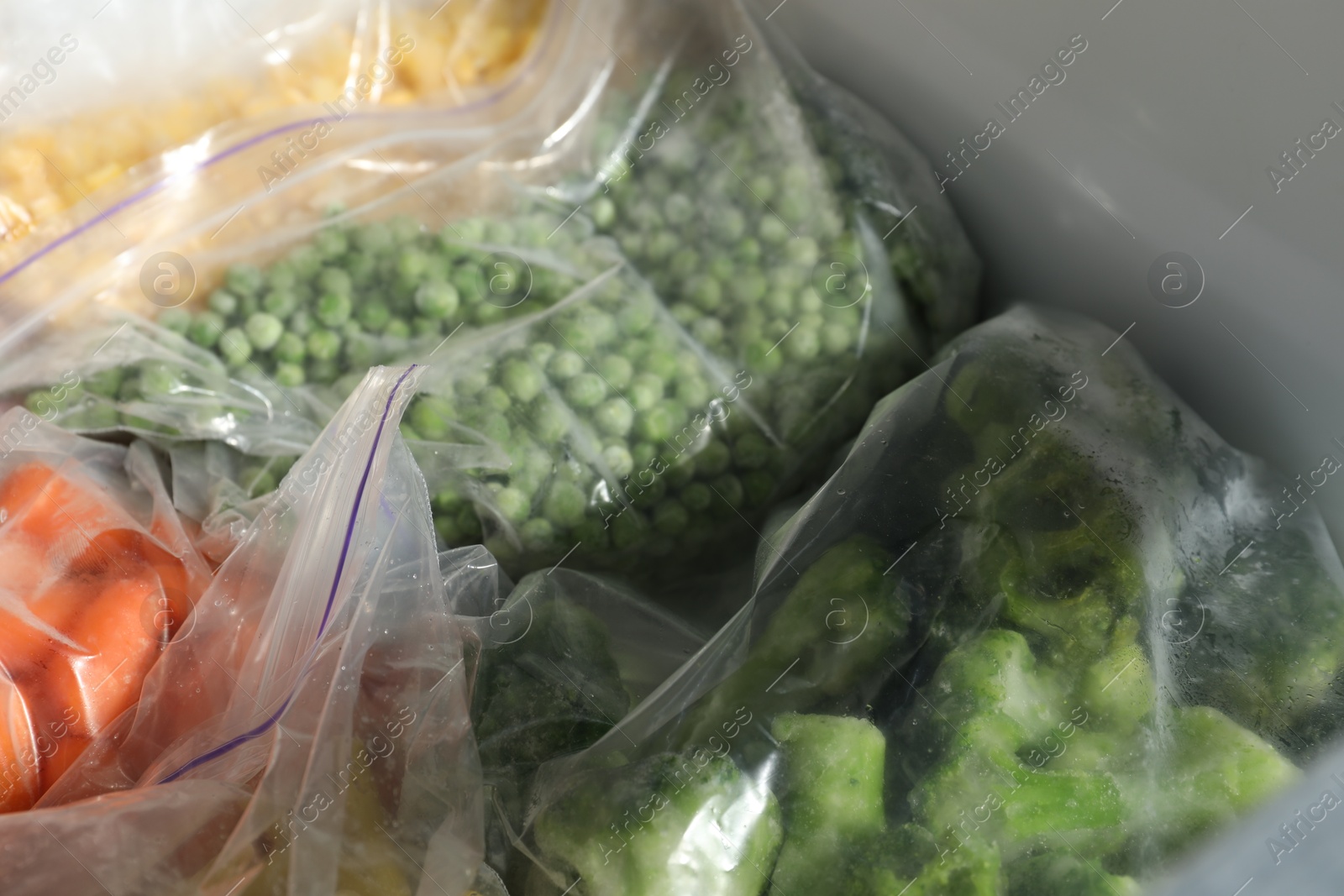 Photo of Plastic bags with different frozen vegetables in refrigerator, closeup