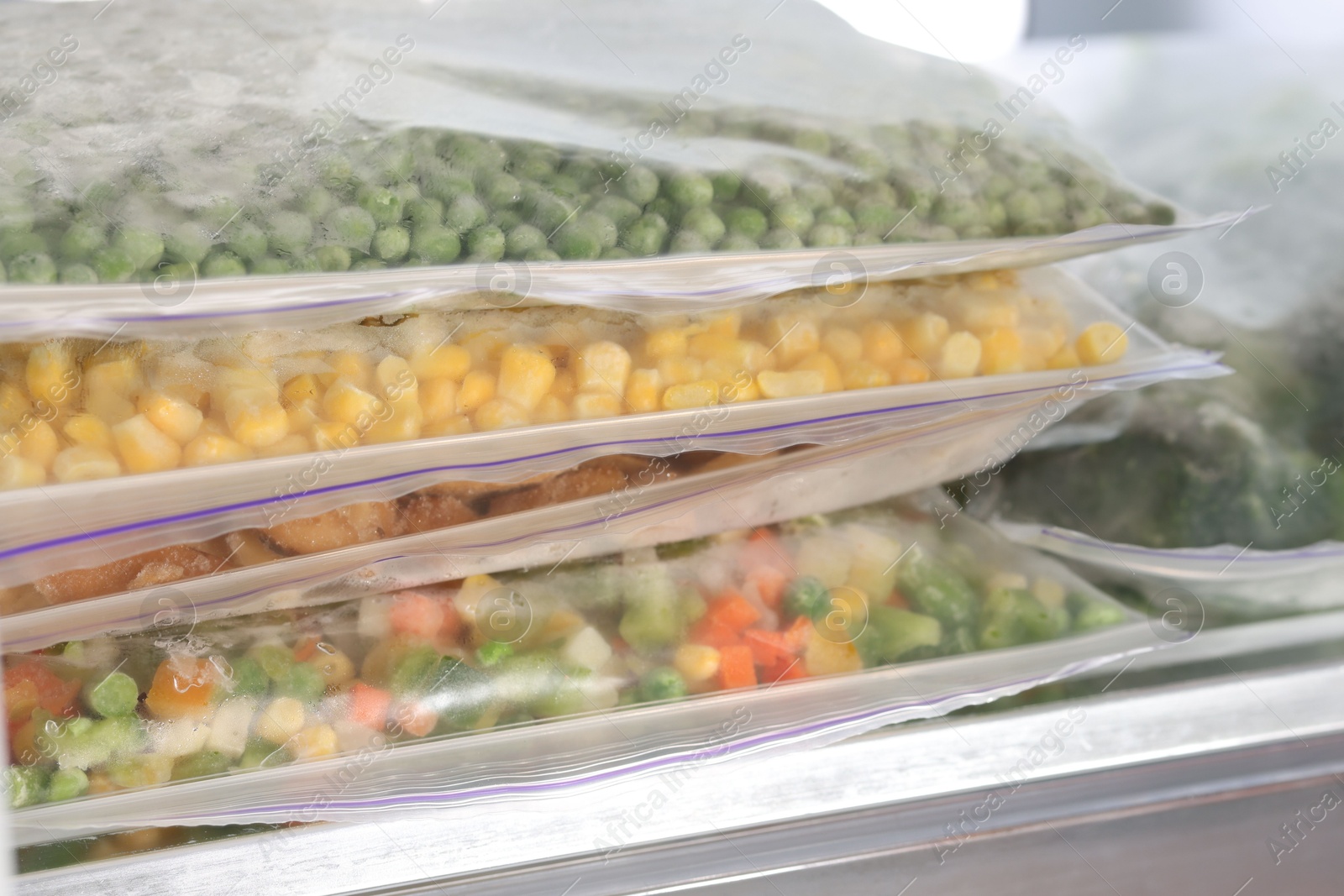 Photo of Plastic bags with different frozen vegetables in refrigerator, closeup