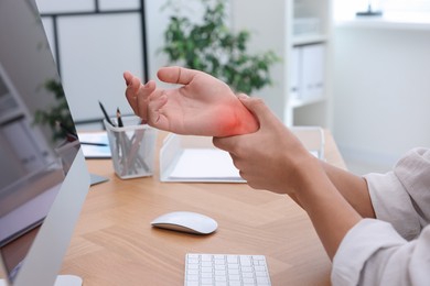 Image of Man suffering from pain in wrist at wooden table, closeup. Office work, Carpal tunnel syndrome