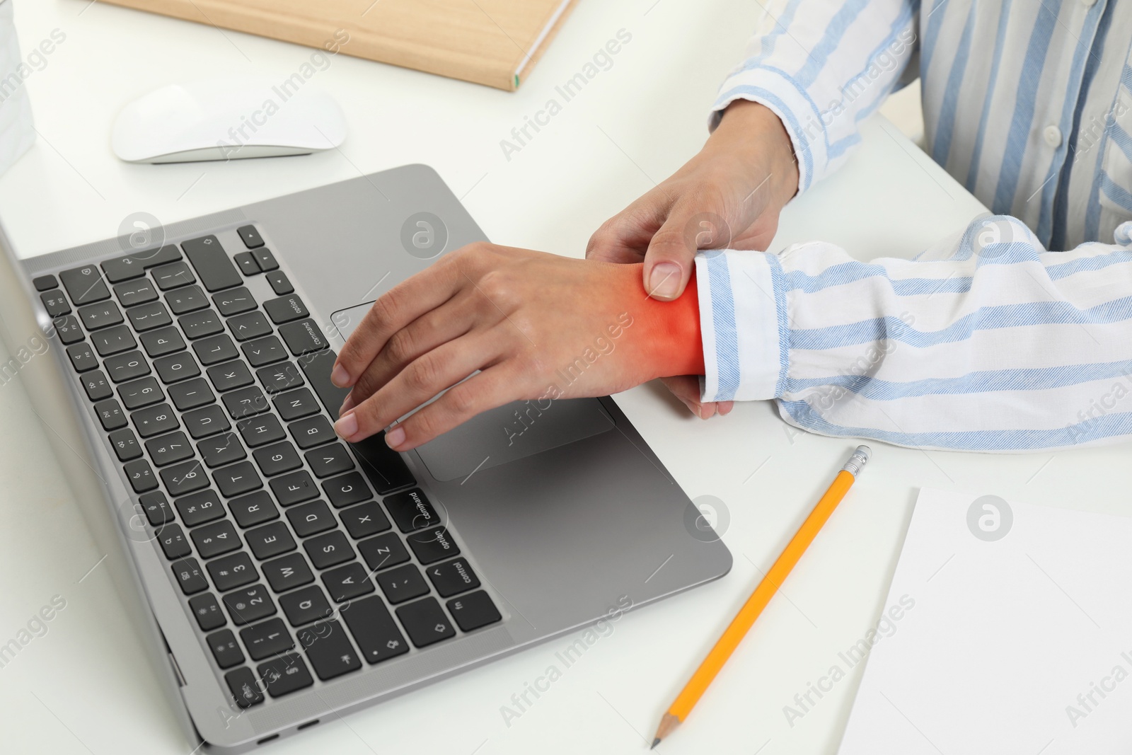 Image of Woman suffering from pain in wrist at table with laptop, closeup. Office work, Carpal tunnel syndrome