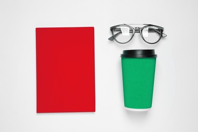 Image of Red notebook, green takeaway cup and glasses on white background, top view