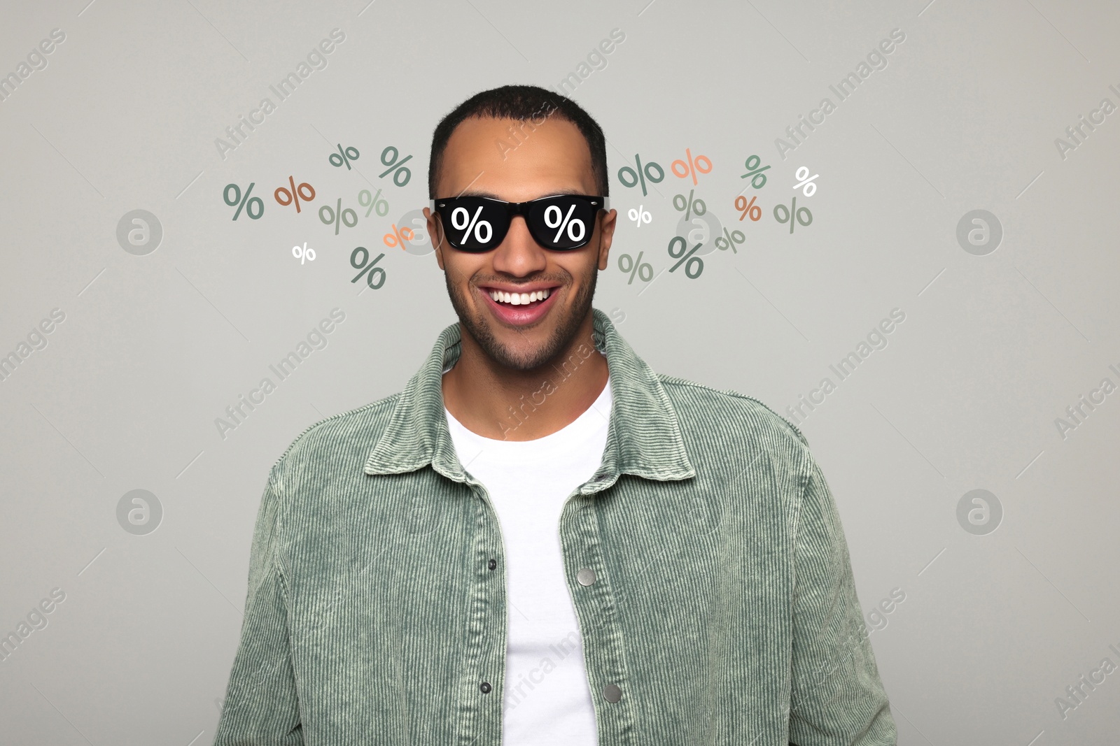 Image of Man with sunglasses smiling on grey background. Percent signs on lenses. Discount, hot offer