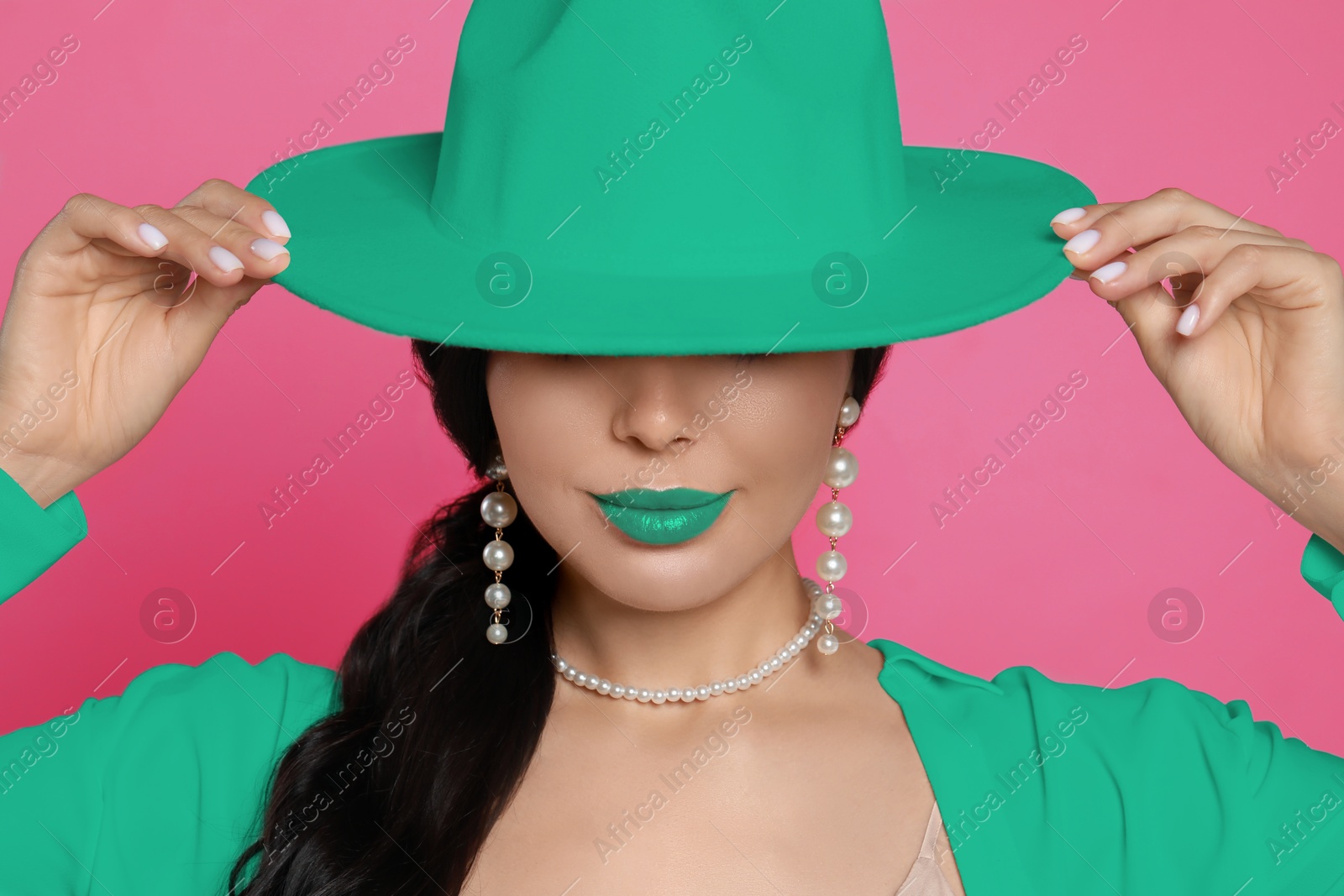 Image of Fashionable woman with aquamarine color lipstick, hat and jacket on pink background