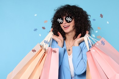 Image of Woman with sunglasses and shopping bags on light blue background. Percent signs on lenses. Discount, hot offer