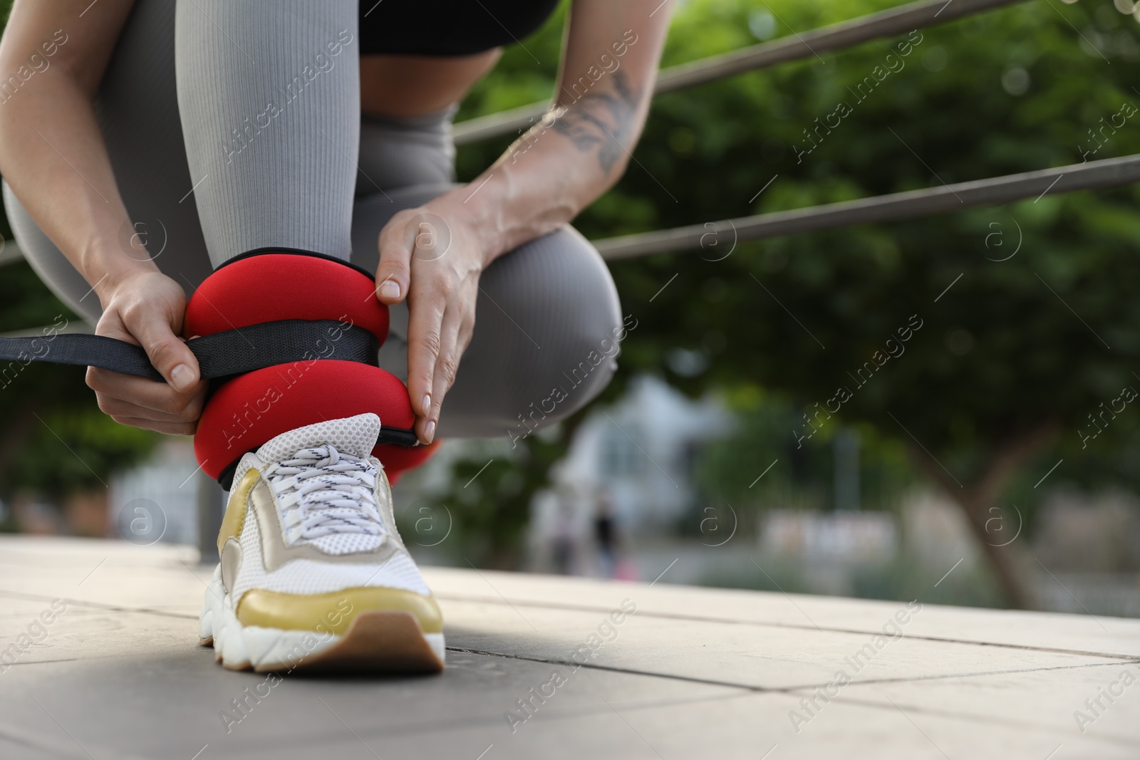 Photo of Woman putting on ankle weights outdoors, closeup. Space for text