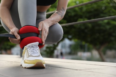 Photo of Woman putting on ankle weights outdoors, closeup. Space for text