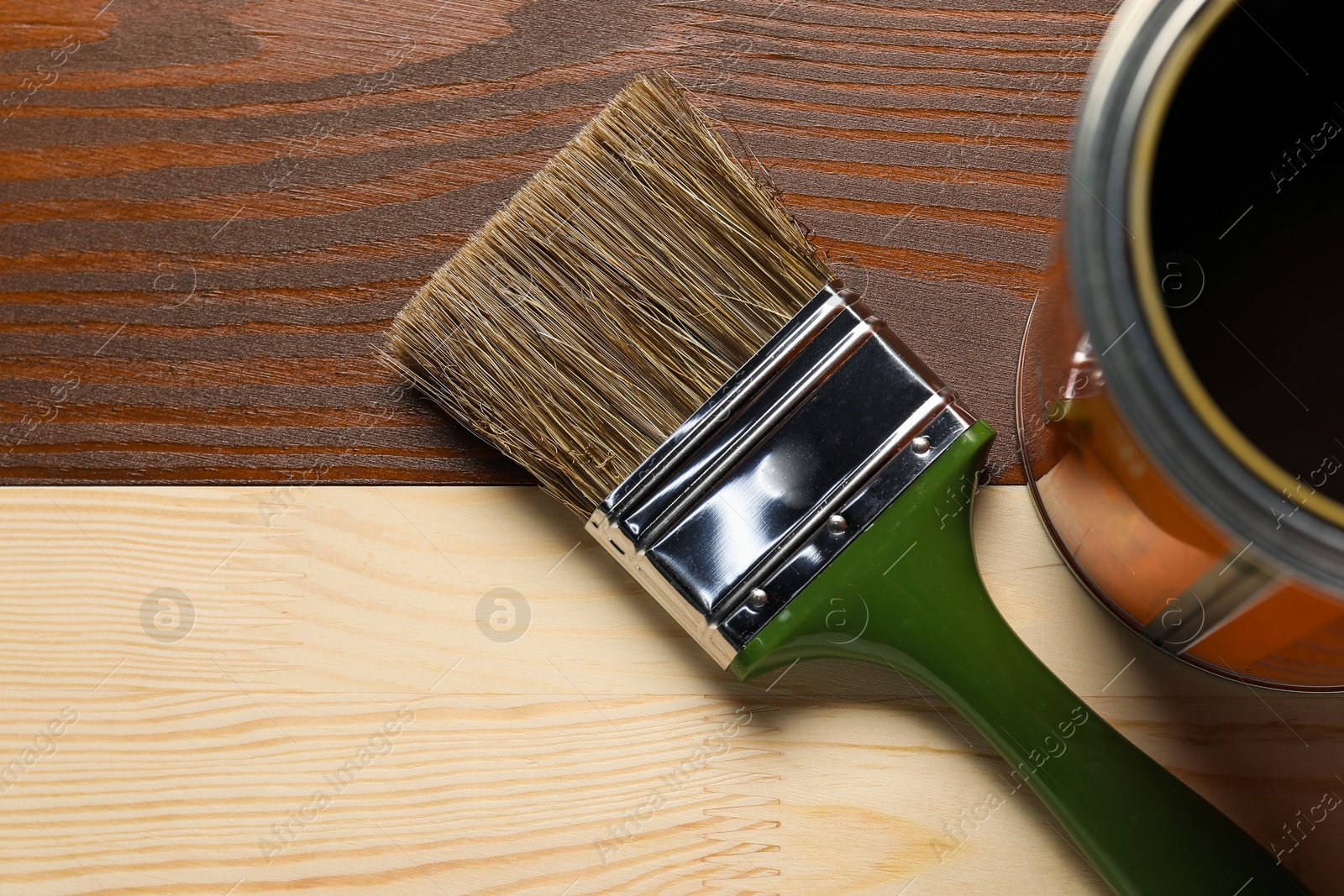 Photo of Applying walnut wood stain. Brush and can on wooden surface, flat lay