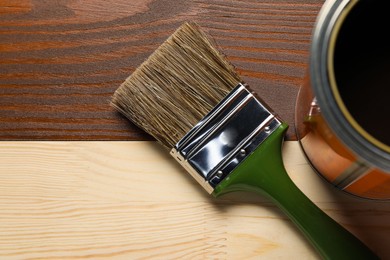 Photo of Applying walnut wood stain. Brush and can on wooden surface, flat lay