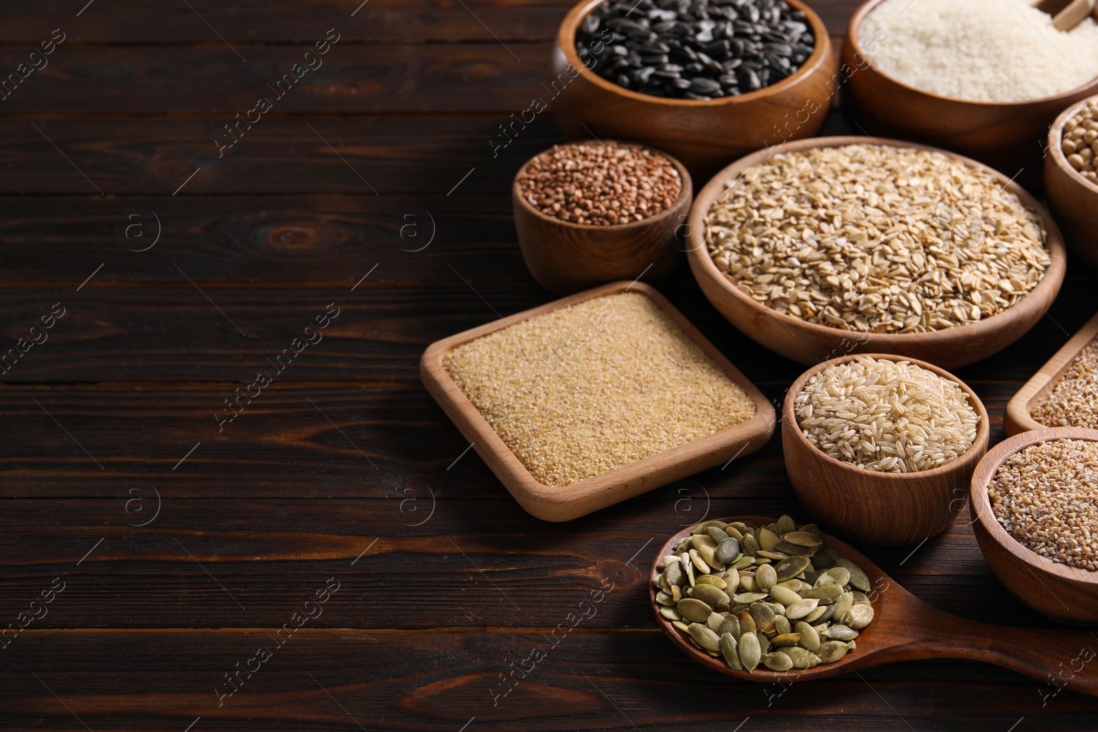 Photo of Different types of cereals and seeds on wooden table, space for text