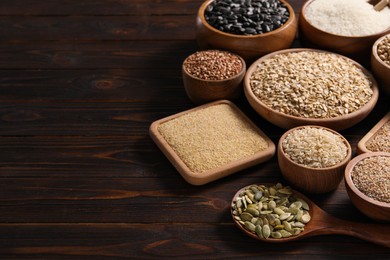 Different types of cereals and seeds on wooden table, space for text