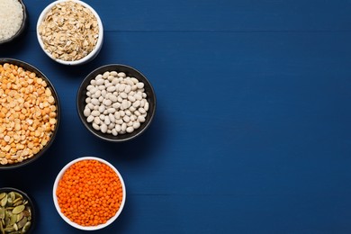 Photo of Different types of cereals, seeds and legumes on blue wooden table, flat lay. Space for text