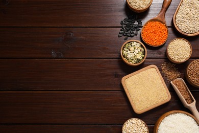 Different types of cereals, seeds and legumes on wooden table, flat lay. Space for text