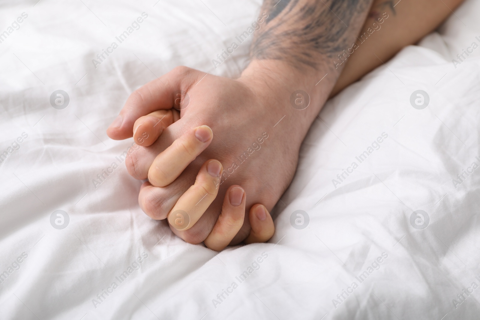 Photo of Lovely couple holding hands in bed, closeup